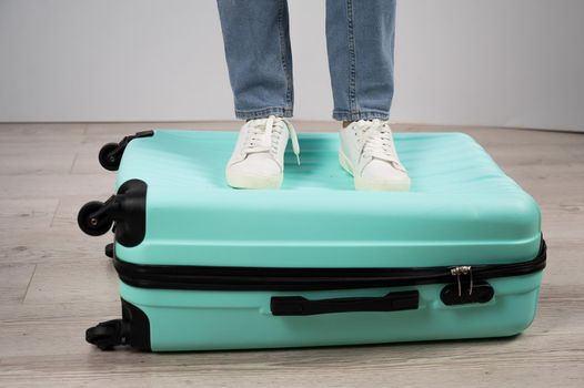 Woman standing with her feet on a suitcase