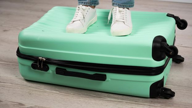 Woman standing with her feet on a suitcase