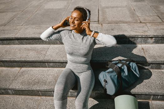 Sporty woman in headphones listening to music after training outdoors. Active lifestyle