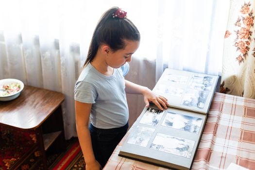 Adorable girl browsing an family album. Vintage style.