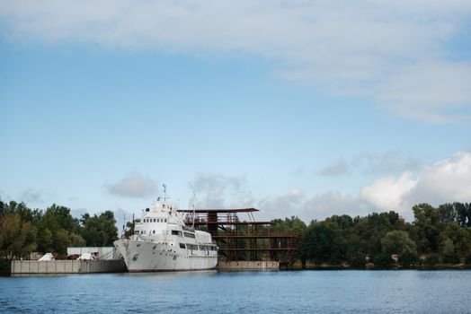 an old white ship with traces of rust stands in a repair shipyard