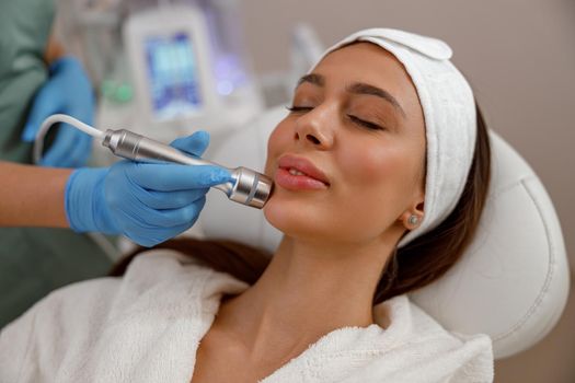 Young woman getting aesthetic facial skin treatment in modern beauty spa salon