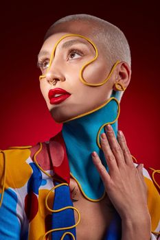 Studio shot of a stylish young woman posing against a red background.