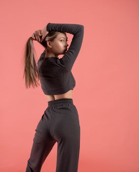 a beautiful slender girl in a stylish home suit on a pink background