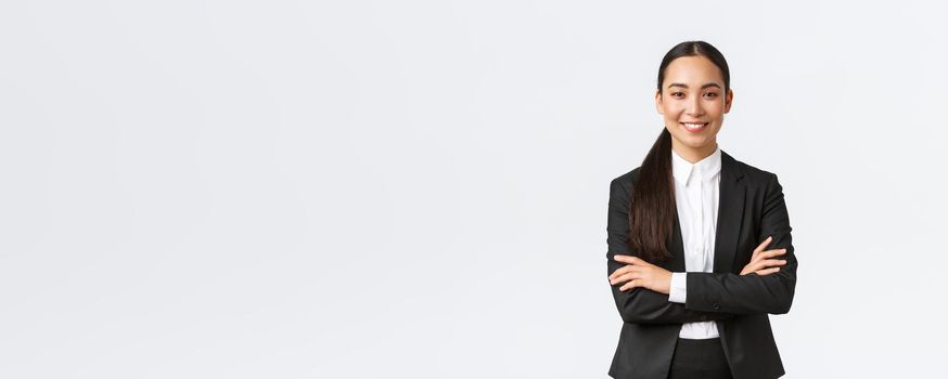 Successful young asian businesswoman in suit ready do business, cross arms confident and smiling. Female entrepreneur determined to win. Happy saleswoman talking to clients, white background.