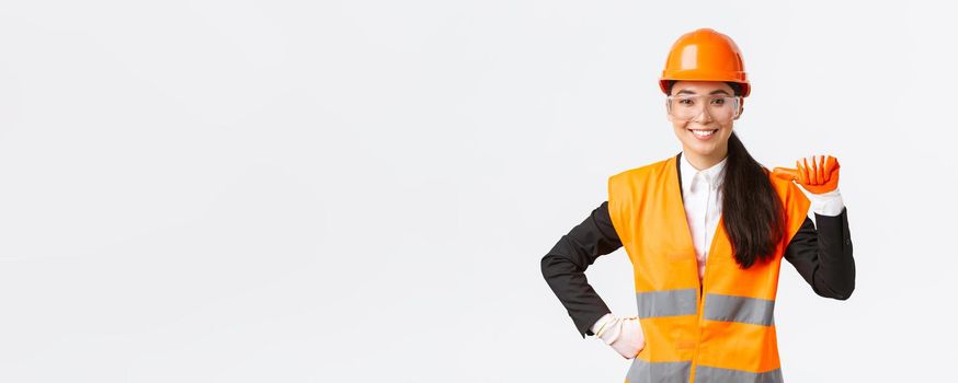 Professional and talented confident smiling asian female engineer, construction architect in safety helmet and glasses, pointing at herself proud, promote own abilities and skills, white background.