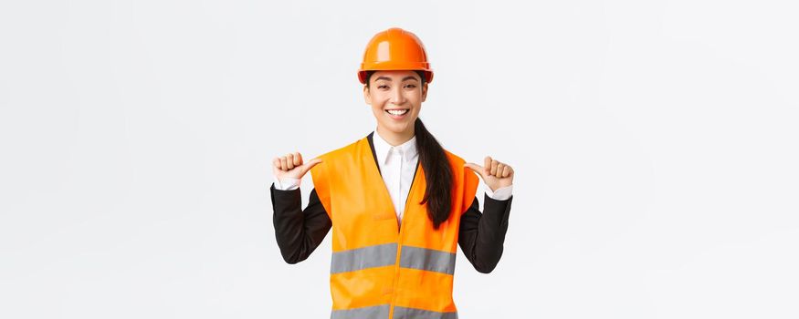 Successful proud smiling asian female construction manager, engineer in safety helmet pointing at herself, show-off. Architect recommend personal assistance, bragging accomplishments.