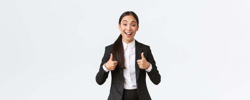 Excited happy saleswoman praise friend work, showing thumbs-up in approval and smiling surprised, congratulate with great deal. Businesswoman satisfied with amazing result.