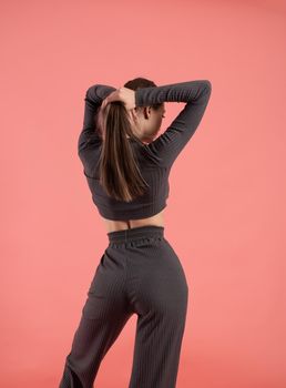 a beautiful slender girl in a stylish home suit on a pink background