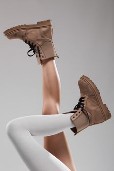 Sexy female legs wearing boots. One leg with white leggings.