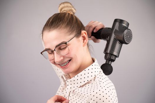 Smiling woman with braces uses a massager gun for her back