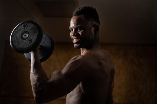 Attractive african american man smiling and doing exercise with dumbbells