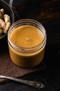 Fresh made creamy Peanut Butter set, on old dark wooden table background