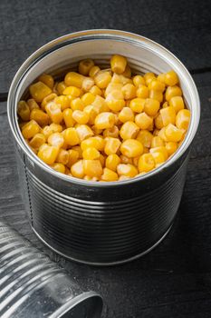 Canned sweet corn in can, on black wooden table background