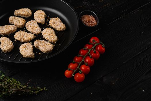 Homemade Raw Breaded Chicken Nuggets, on black wooden table background, with copy space for text