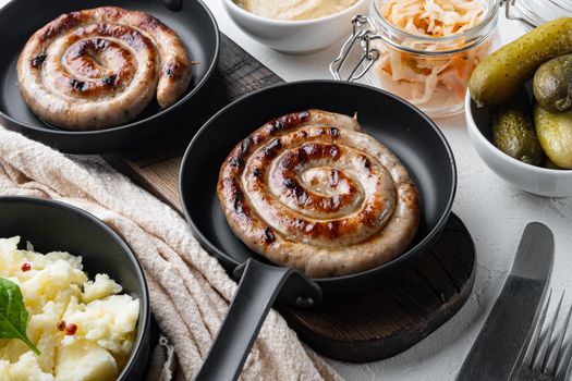 Grilled Spiral sausage set in cast iron frying pan, on white background