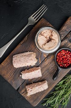 Canned tuna fillet meat in olive oil, on black background, top view