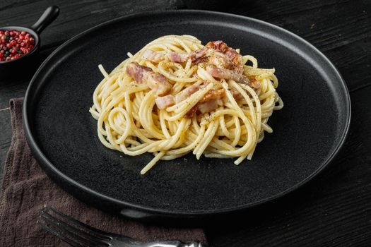 Carbonara pasta dish. Traditional Roman cuisine. Italian food set, on black wooden background