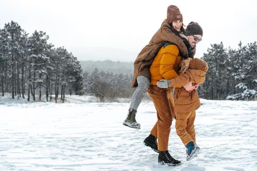 Happy family having a walk in winter outdoors in snow forest