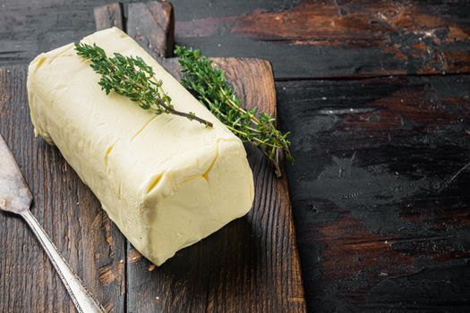 Pat of farm fresh butter, on old dark wooden table background with copy space for text