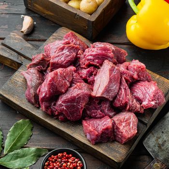 Fresh raw chopped beef set with sweet bell pepper, on old dark wooden table, square format