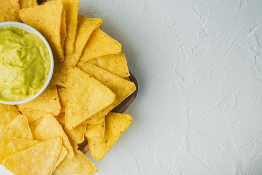 Triangular yellow corn tortilla chip with sauces, on white background, top view or flat lay with copy space for text