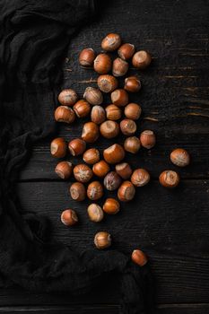 Hazelnuts brown wooden shell set, on black wooden table background, top view flat lay