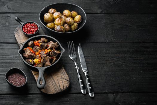 Beef bourguignon stew with vegetables set, in cast iron frying pan, on black wooden background, with copy space for text