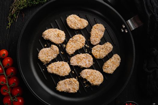 Homemade Raw Breaded Chicken Nuggets, on black wooden table background, top view flat lay