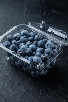 Blueberries, in clear plastic tray, on black background