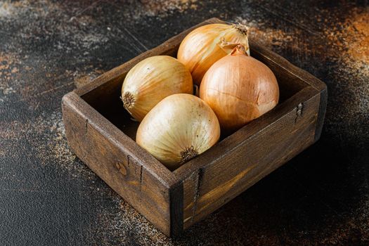 Unpeeled raw yellow onion, on old dark rustic background