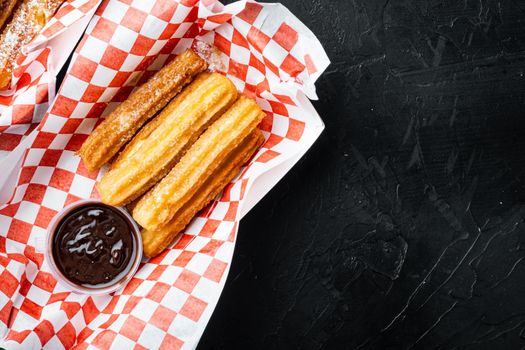 Churros with sugar powder, in the box in paper tray, on black background, top view flat lay with space for text, copyspace