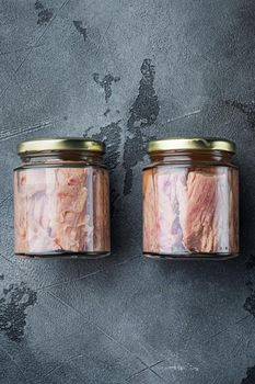 Tuna fillet meat in glass jar, on gray background, flat lay