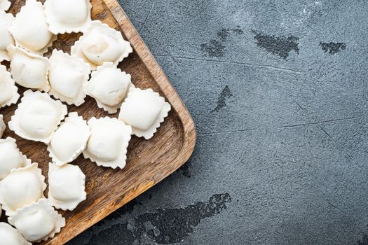 Frozen dumplings tortellini and ravioli set in wooden box, on gray background, top view flat lay , with copyspace and space for text