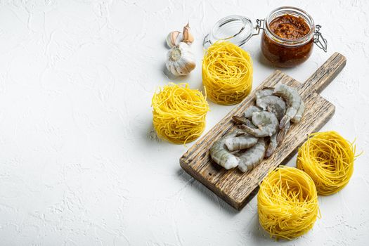 Pasta with shrimp, tomato and pesto sauce ingredients set, on white stone surface, with copy space for text