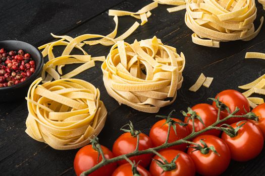 Ingredient of traditional mediterranean cuisine Uncooked pasta tagliatelle set, on black wooden table background