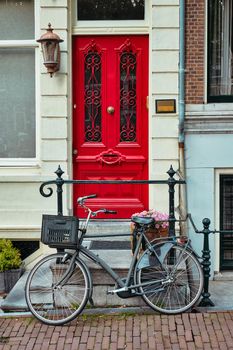 Bicycle near door of old house in Amsterdam street. Bicycles are the very popular means of transport in Netherlands. Amsterdam, Netherlands