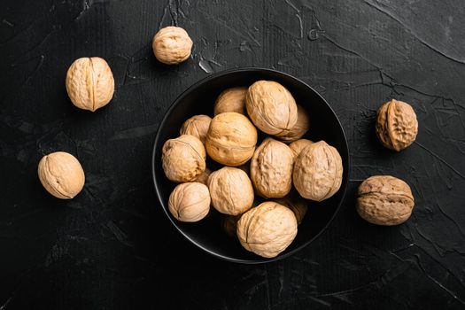 Walnut whole nut set, on black dark stone table background, top view flat lay