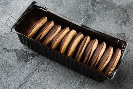 Chocolate coated biscuit cakes set, in plastic tray container, on gray background