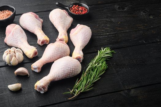 Fresh chicken meat cuts Farm poultry meat set, with seasoning and herbs rosemary and thyme, on black wooden table background, with copy space for text