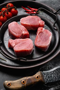 Organic pork meat chops, on black dark stone table background