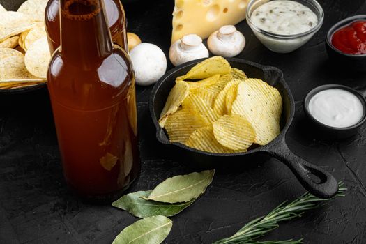 Potato chips. Beer snacks, sauce set, on black stone background