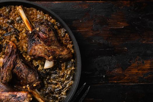 Baked lamb shank with barley and ale set, on old dark wooden table background, top view flat lay, with copy space for text