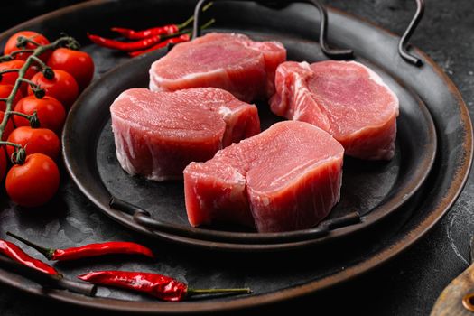 Raw pork fillet with spices, on black dark stone table background