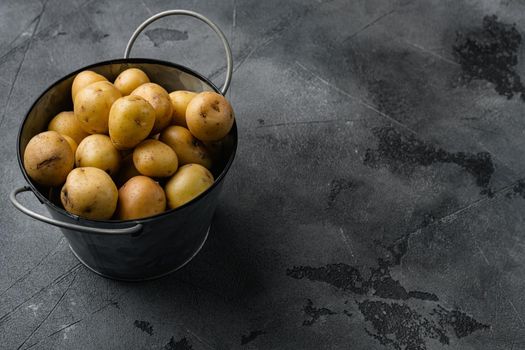 Raw baby new potatoes set, on gray stone table background, with copy space for text