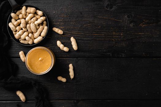 Peanut butter and peanut beans set, on black wooden table background, top view flat lay, with copy space for text