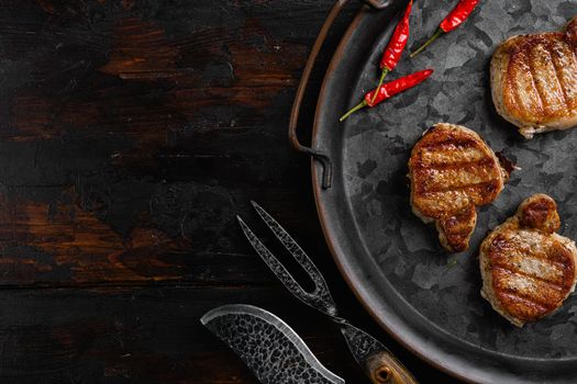 Medallions steaks from pork tenderloin, on old dark wooden table background, top view flat lay, with copy space for text