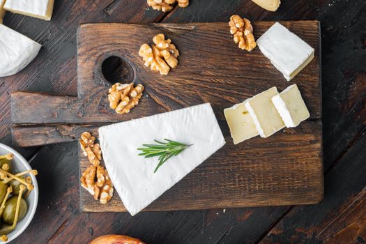 Brie type of cheese set, on dark wooden background, flat lay