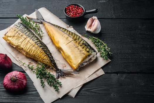 Appetizing smoked fish mackerel, on black wooden table background with copy space for text