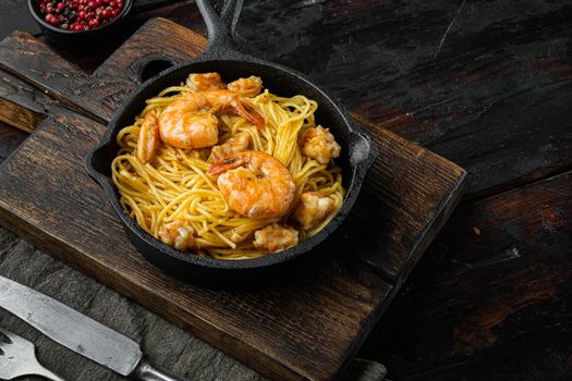 Noodles with seafood set, in cast iron frying pan, on old dark wooden table